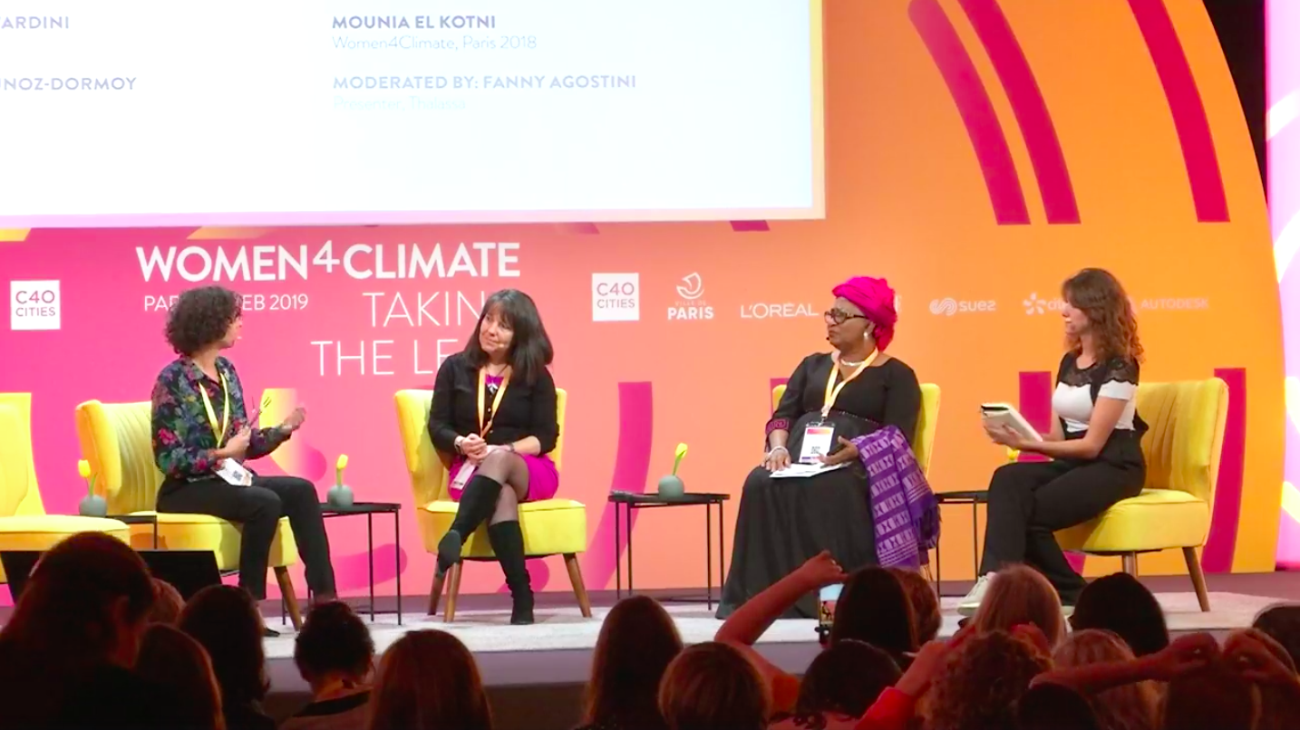 4 femmes assises sur des chaises jaunes sur une estrade avec fond orange.